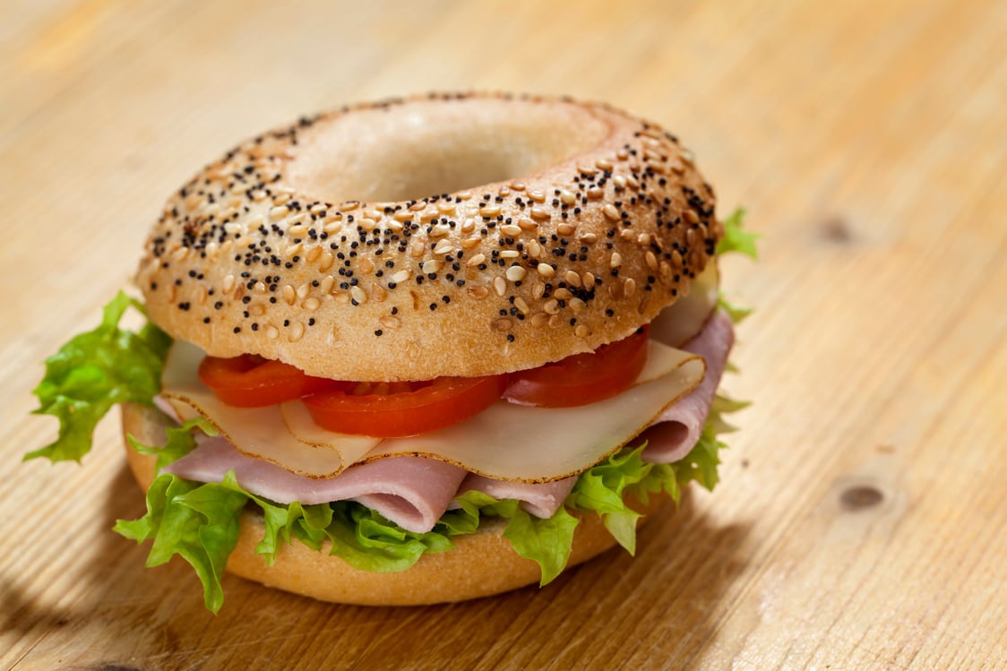 Ham and cheese bagel on a wooden board